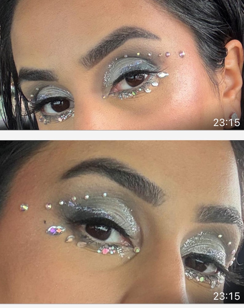 May include: Close-up of two eyes with silver and gray eyeshadow, glitter, and rhinestones. The makeup design includes rhinestones above and below the eyes, with a time stamp of 23:15 in the bottom right corner.
