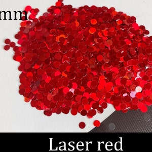 Pu&ograve; includere: Un'immagine ravvicinata di glitter laser rosso da 3 mm. Il glitter ha la forma di piccoli cerchi rotondi.