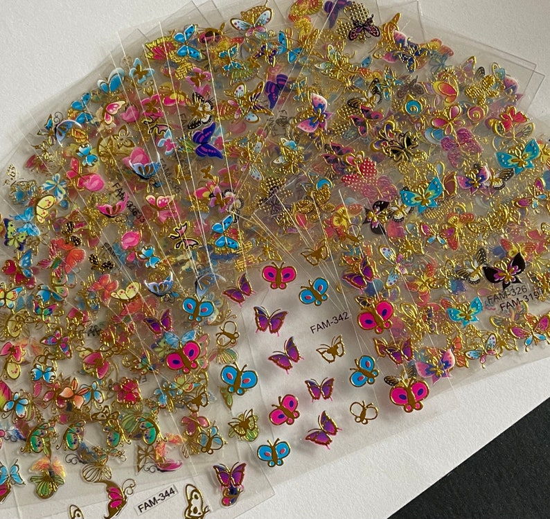 May include: A set of 10 sheets of gold butterfly stickers. Each sheet features a variety of colorful butterflies with gold accents. The sheets are labeled with the product codes FAM-3441, FAM-342, and FAM-3151.