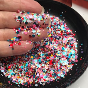 Pu&ograve; includere: Primo piano di una ciotola nera piena di coriandoli colorati. I coriandoli sono un mix di cerchi piccoli e grandi in varie tonalit&agrave; di rosso, rosa, blu, verde, giallo e bianco.