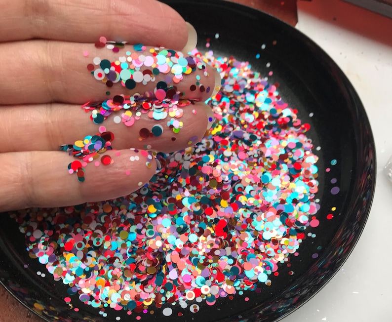 Pu&ograve; includere: Primo piano di una ciotola nera piena di coriandoli colorati. I coriandoli sono un mix di cerchi piccoli e grandi in varie tonalit&agrave; di rosso, rosa, blu, verde, giallo e bianco.