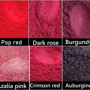 May include: Six small containers of red, pink and purple pigment powder. The containers are labelled "Pop red", "Dark rose", "Burgundy", "Azalia pink", "Crimson red", and "Aubergine".