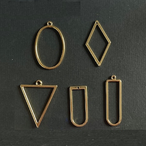 Peut inclure: Cinq cadres de pendentif en métal doré de formes différentes : ovale, diamant, triangle, rectangle et rectangle long. Les cadres mesurent environ 5 cm de haut.
