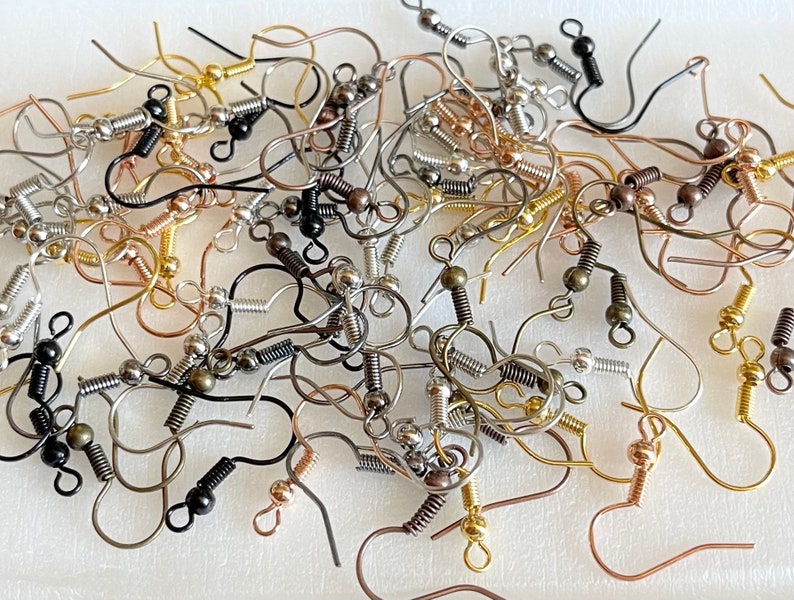 May include: A large assortment of earring hooks in various finishes, including silver, gold, and bronze. The hooks are made of metal and have a spring-loaded closure.