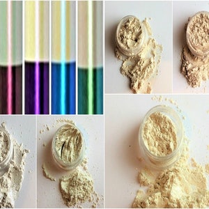 May include: Four small jars of loose, shimmery, light beige eyeshadow pigment. The jars are open and some of the pigment has spilled out.