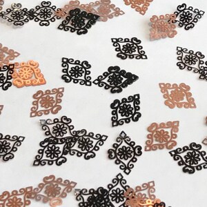 May include: Assortment of black and copper metallic decorative embellishments in a diamond shape with a floral design.