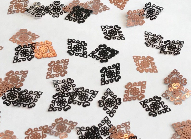 May include: Assortment of black and copper metallic decorative embellishments in a diamond shape with a floral design.