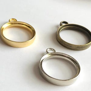 Op de afbeelding: Drie ronde metalen hangerframes met een lus aan de bovenkant. De frames zijn goud, zilver en brons.