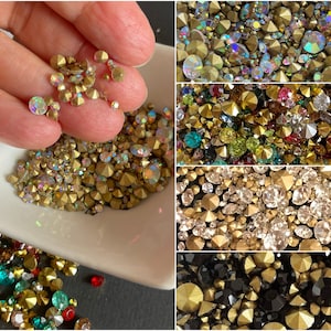 May include: Assortment of colorful rhinestones in various sizes and shapes. The rhinestones are displayed in a white bowl and on a black surface. The rhinestones are perfect for crafting, jewelry making, and decorating.