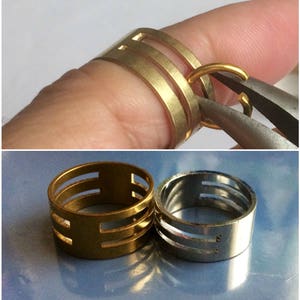 May include: Gold-toned metal rings with a layered design. One ring is being worked on with pliers. Another ring is on a finger. A silver-toned ring with the letter "S" is also shown. Jewelry.