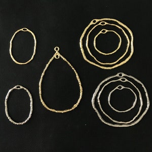 May include: Six different metal rings and teardrop shapes, some with a hammered texture, in gold and silver tones. These are jewelry findings for crafting.