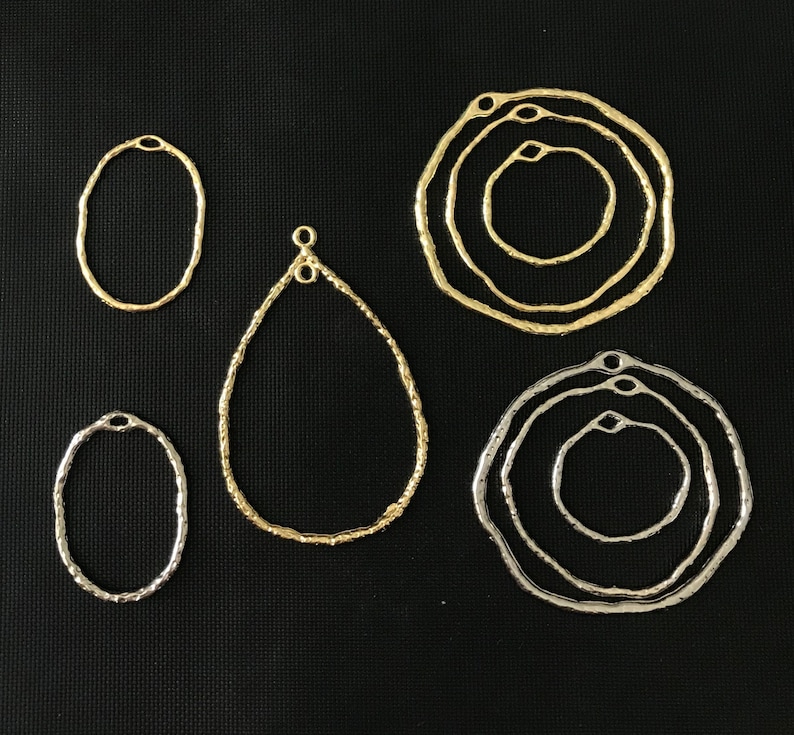 May include: Six different metal rings and teardrop shapes, some with a hammered texture, in gold and silver tones. These are jewelry findings for crafting.