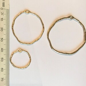 May include: Three silver metal hoops of different sizes. The hoops are textured and have a hammered finish.
