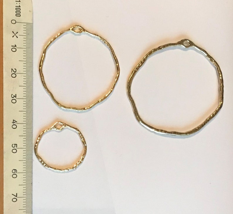 May include: Three silver metal hoops of different sizes. The hoops are textured and have a hammered finish.