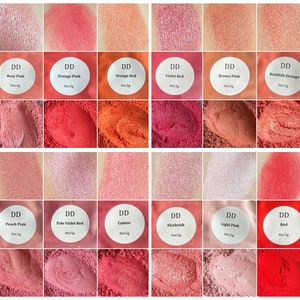 May include: A collection of 12 small jars of red, pink, and orange pigment powder. Each jar has a white label with the text "DD" and the name of the color, such as "Rosy Pink" or "Orange Red".