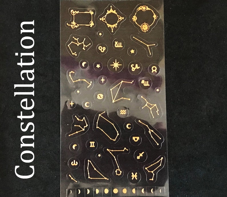 May include: A sheet of gold constellation stickers on a black background. The stickers feature various constellations, stars, and zodiac symbols.