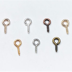 Op de afbeelding: Assortiment van schroefoogjes in goud, zilver, brons en koper. Deze oogjes zijn ideaal voor het maken van sieraden en knutselprojecten.