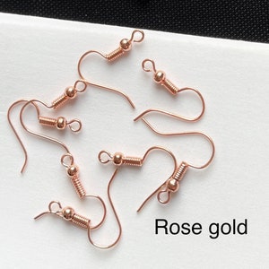 May include: Rose gold earring hooks with a spring-loaded closure. The hooks are made of metal and have a shiny finish.