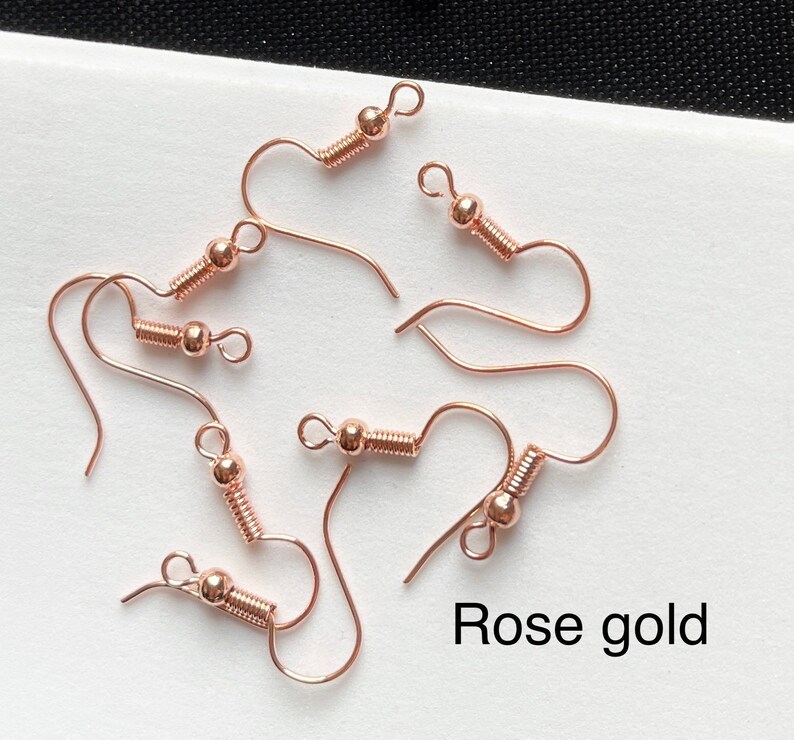 May include: Rose gold earring hooks with a spring-loaded closure. The hooks are made of metal and have a shiny finish.