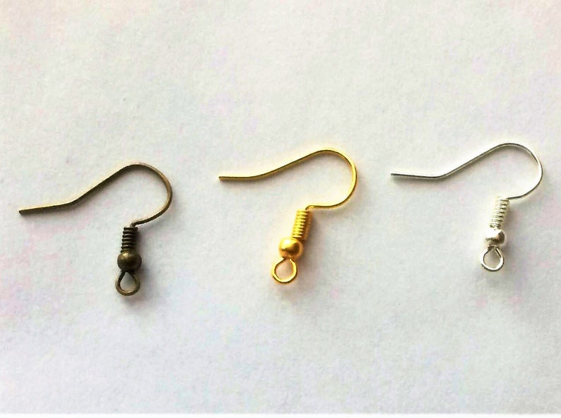 May include: Three earring hooks in different colors: bronze, gold, and silver. Each hook has a small ball at the end and a spring.