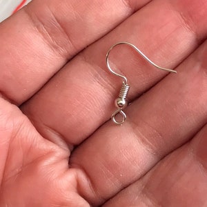 May include: Silver earring hook with a spring closure. The hook is made of metal and has a smooth finish.