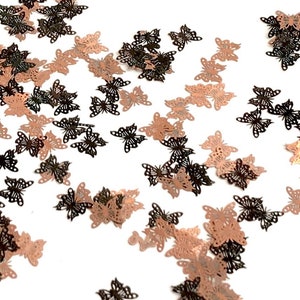 May include: Scattered rose gold and black butterfly confetti. The butterflies are cut-out shapes with a delicate design.