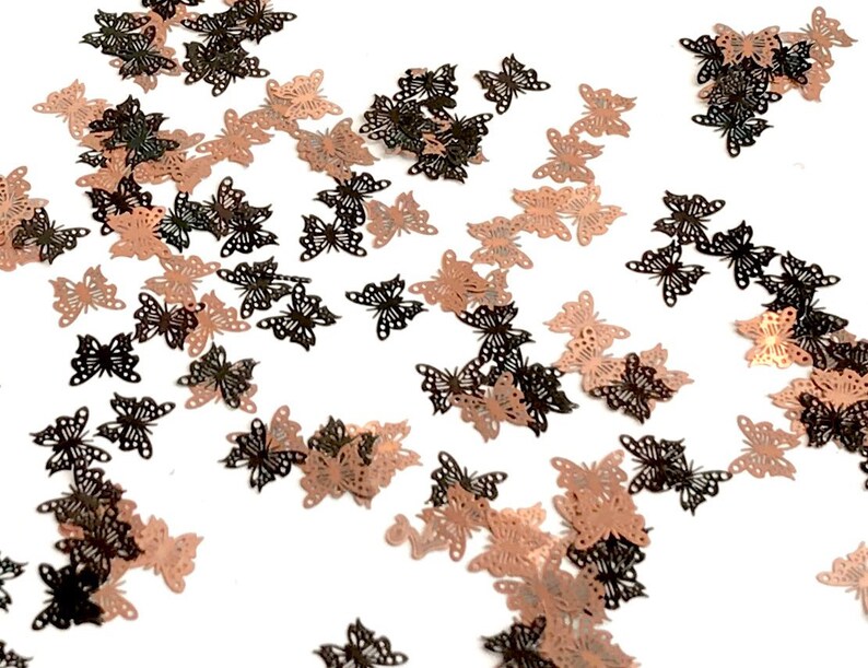 May include: Scattered rose gold and black butterfly confetti. The butterflies are cut-out shapes with a delicate design.