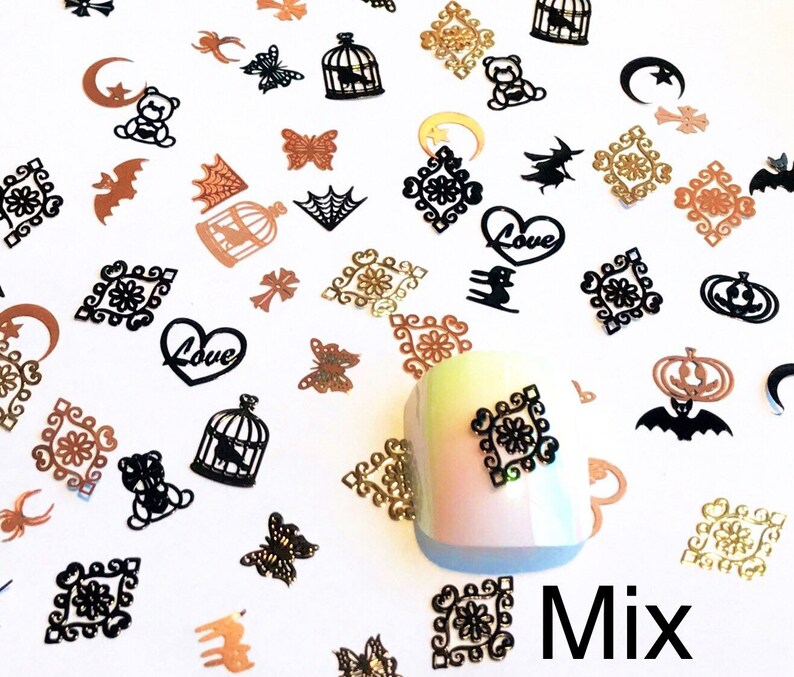 May include: Assortment of black and gold metal nail art charms. The charms include hearts, cages, butterflies, pumpkins, bats, stars, and crescent moons. The word "Love" is written on two of the hearts. The word "Mix" is written on the bottom right of the image.