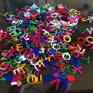 Puede incluir: Un mont&oacute;n grande de confeti de colores con forma de letras. El confeti est&aacute; hecho de material brillante y met&aacute;lico e incluye letras del alfabeto en varios colores, como dorado, plateado, rojo, azul, verde y rosa.