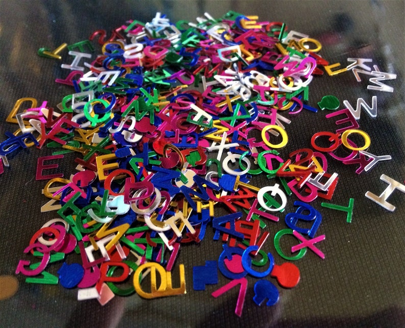 Puede incluir: Un mont&oacute;n grande de confeti de colores con forma de letras. El confeti est&aacute; hecho de material brillante y met&aacute;lico e incluye letras del alfabeto en varios colores, como dorado, plateado, rojo, azul, verde y rosa.