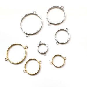 May include: A collection of round metal bezel settings in various sizes and colors, including silver and gold. Each bezel has small loops for attaching to other components, perfect for jewelry making or crafting projects.