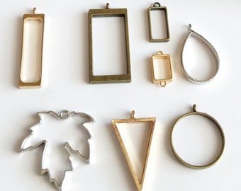 May include: Assortment of eight different metal pendant frames for resin jewelry making. The frames are in various shapes, including a rectangle, circle, teardrop, triangle, and leaf. The frames are made of gold and silver metal.