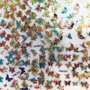 May include: Assortment of colorful butterfly stickers with gold accents. The stickers feature various butterfly designs and colors, including blue, pink, purple, and green. The stickers are arranged in rows on a white background. The stickers are labeled with product codes, including "FAM-328", "FAM-316", "FAM-323", and "M-336".