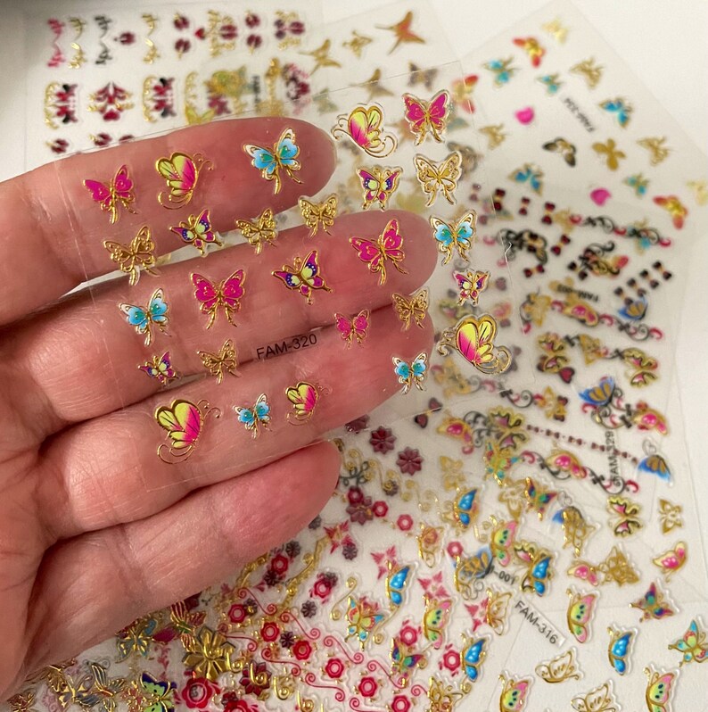 May include: A sheet of clear nail stickers with gold and colorful butterfly designs. The sheet is labeled "FAM-320".
