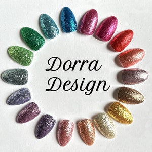 May include: A variety of glitter nail polish colors arranged in a circle. The colors include green, blue, purple, pink, red, gold, silver, and more. The text "Dorra Design" is in the center of the circle.