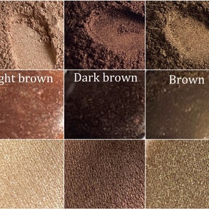 May include: Close-up of nine eyeshadow samples in various shades of brown. The samples are arranged in a 3x3 grid. The top row shows light brown, dark brown, and brown. The middle row shows a darker shade of brown, a very dark brown, and a medium brown. The bottom row shows a light beige, a medium brown, and a light brown with gold shimmer.