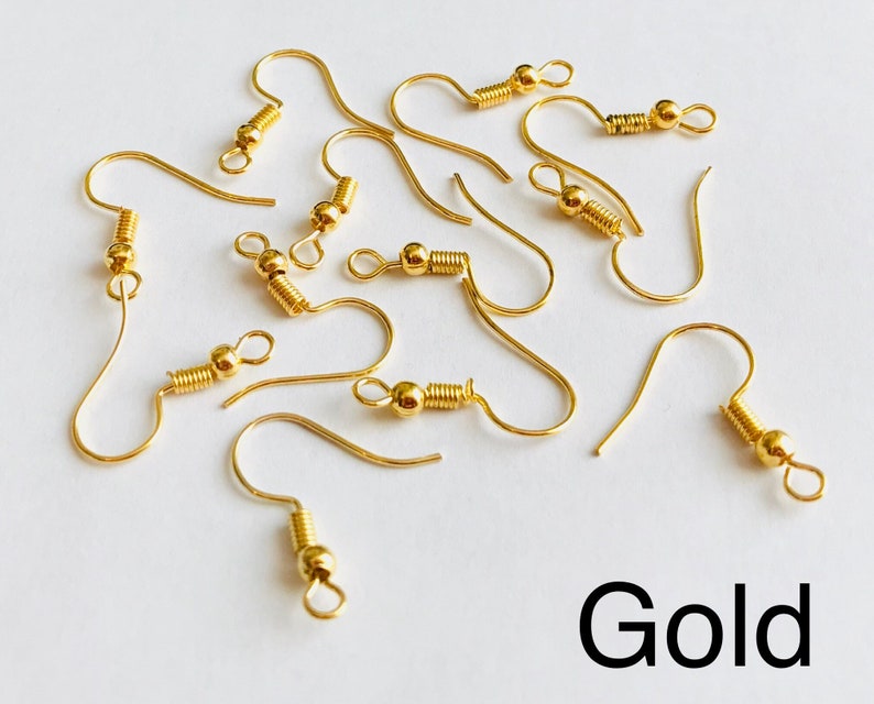 May include: A close-up of ten gold earring hooks. The hooks are made of metal and have a spring-loaded closure.