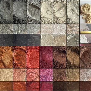 May include: A collection of 36 small jars of mica powder in various colors, including black, white, gold, silver, red, brown, and green. The jars are arranged in a grid pattern.