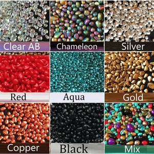 Op de afbeelding: Assortiment van glazen kralen in verschillende kleuren, waaronder helder, kameleon, zilver, rood, aqua, goud, koper, zwart en een mix van kleuren. De kralen zijn klein en hebben een afgeronde vorm.