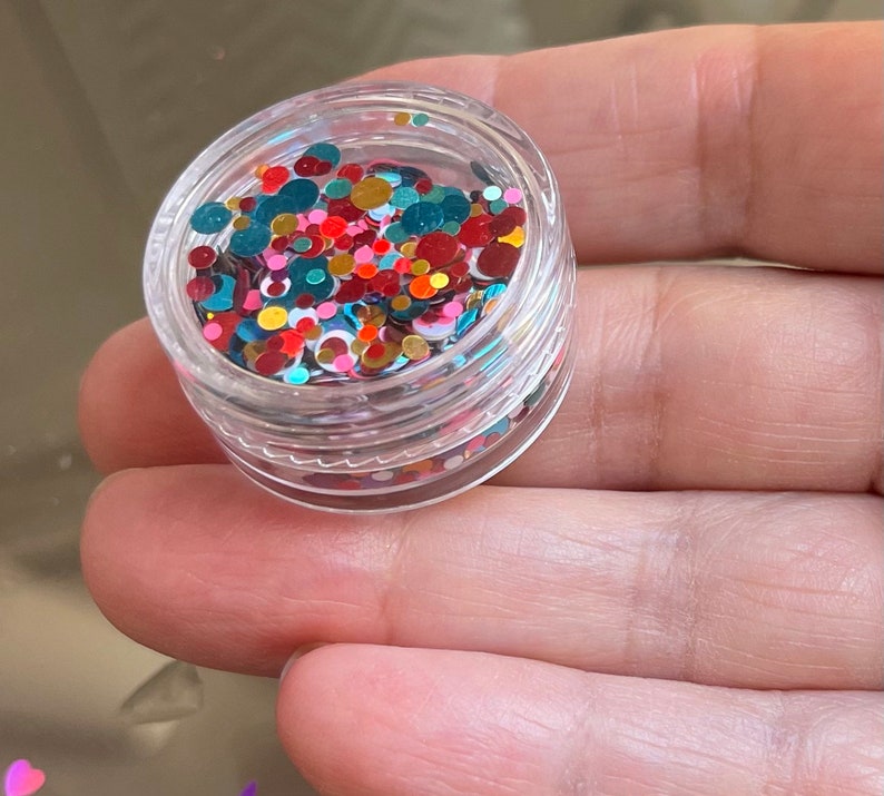 Pu&ograve; includere: Un piccolo barattolo trasparente pieno di glitter rotondi colorati. Il glitter &egrave; un mix di rosso, verde, oro e bianco.