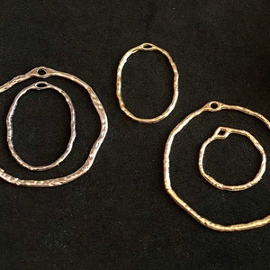 May include: Four silver and gold metal hoops of varying sizes. The hoops are all circular and have a hammered texture.