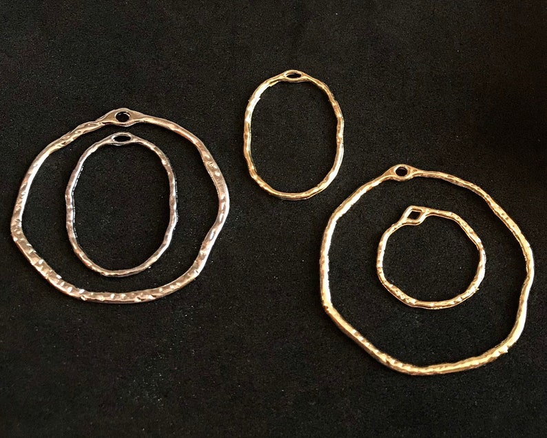 May include: Four silver and gold metal hoops of varying sizes. The hoops are all circular and have a hammered texture.