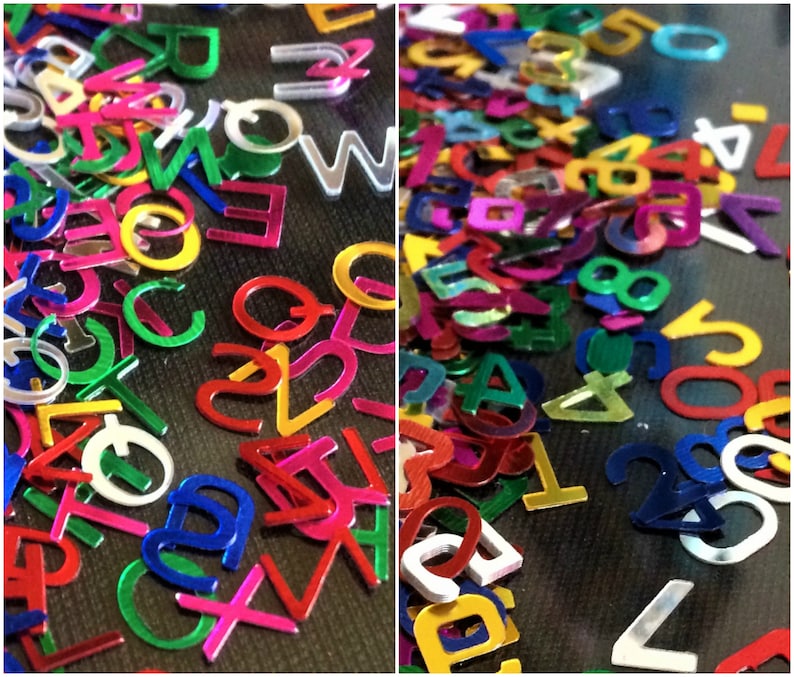 Puede incluir: Primer plano de pegatinas de letras y n&uacute;meros de colores. Las pegatinas est&aacute;n hechas de material met&aacute;lico brillante y est&aacute;n esparcidas sobre una superficie oscura. Las letras y los n&uacute;meros son de varios colores, incluyendo rojo, azul, verde, amarillo y plateado.