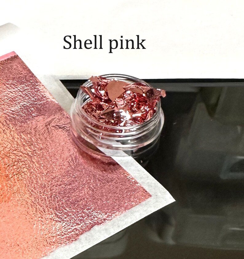 May include: A small clear jar filled with loose, thin, metallic flakes in a shell pink color. The text "Shell pink" is written above the jar.