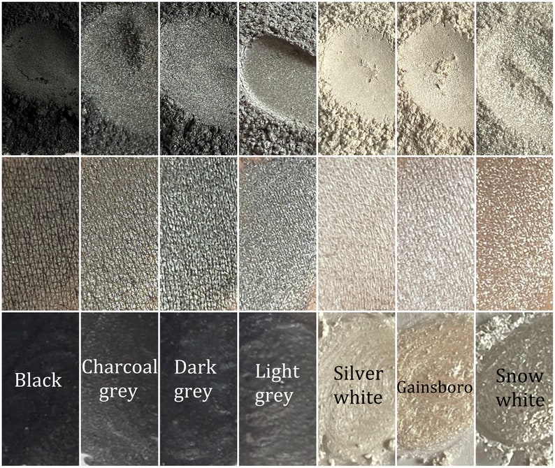 May include: A collection of eight eyeshadow samples in shades of gray and white. The shades are labeled "Black", "Charcoal grey", "Dark grey", "Light grey", "Silver white", "Gainsboro", and "Snow white".