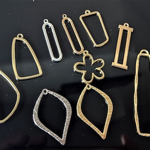 Pode incluir: Conjunto de bases para brincos de metal dourado e prateado em várias formas, incluindo uma flor, um retângulo, um oval e uma lágrima.
