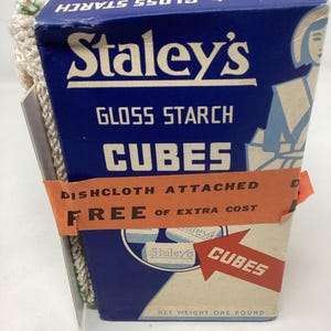 May include: A vintage box of Staley's Gloss Starch Cubes, featuring a blue and white design with the brand name prominently displayed. The box includes the text "Dishcloth Attached FREE of Extra Cost" and "Net Weight One Pound."