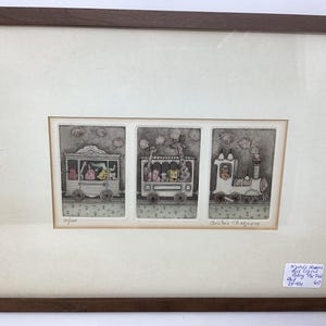 May include: Framed artwork featuring three panels with whimsical train scenes. The panels depict animal passengers in carriages and a locomotive. The artwork is signed and numbered 10/100. The frame is a dark brown wood.