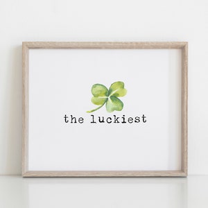 May include: A framed print with a watercolor illustration of a four-leaf clover and the text "the luckiest".