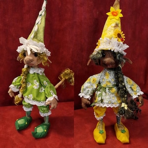 Puede incluir: Dos muñecas de tela hechas a mano con trenzas largas, que llevan vestidos florales verdes y amarillos, sombreros verdes y amarillos y zapatos verdes y amarillos.